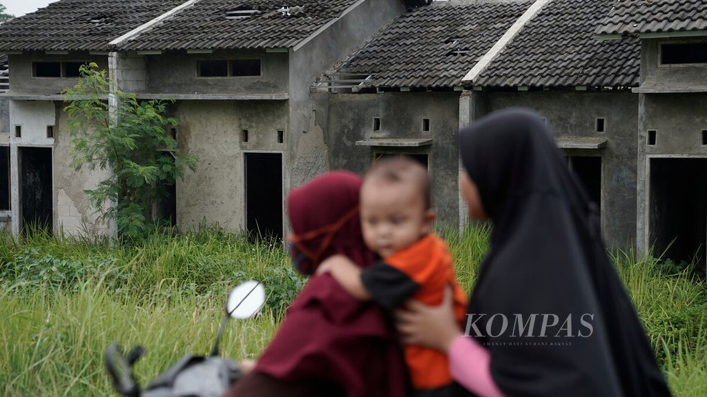 Warga melintasi hunian yang mangkrak di Desa Satria Jaya, Kecamatan Tambun Selatan, Kabupaten Bekasi, Jawa Barat, Kamis (5/11/2020). 