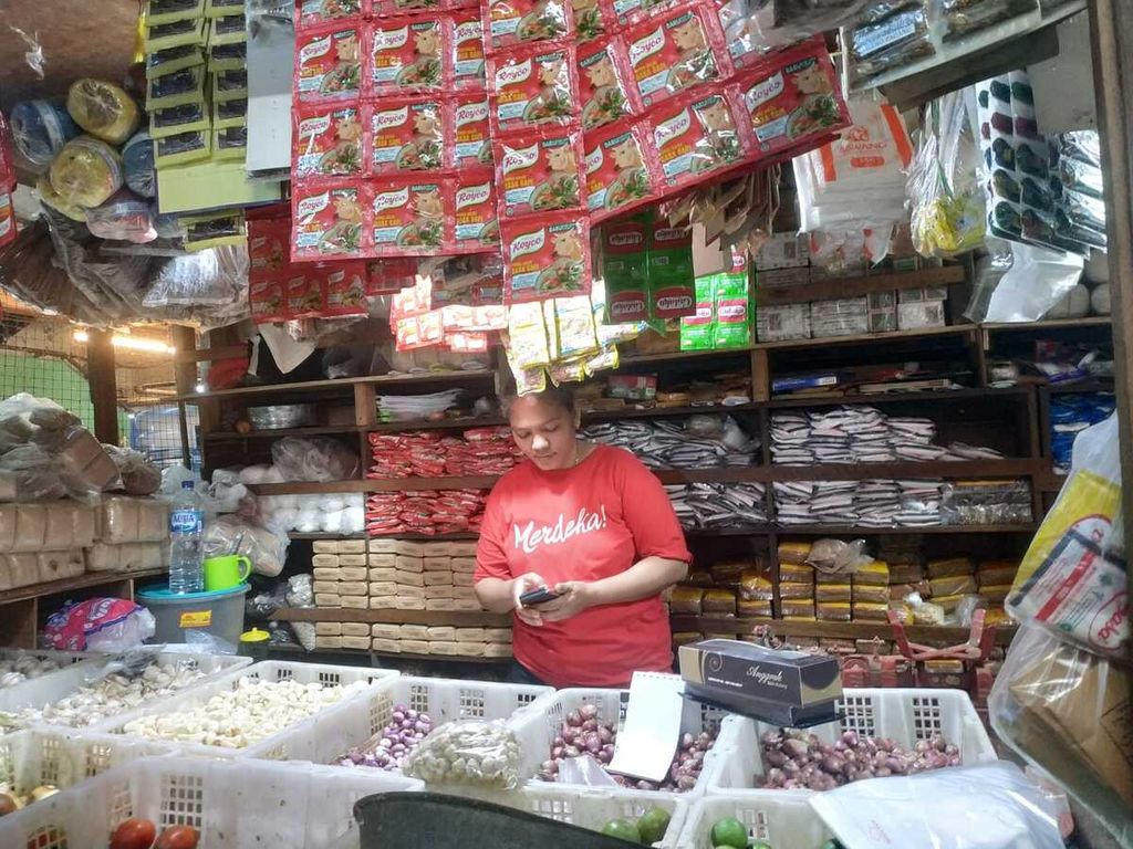Harsini, pedagang bumbu dapur di Pasar Palmerah, Jakarta Pusat, Minggu (9/10/2022), sedang menghitung total belanja pelanggannya.