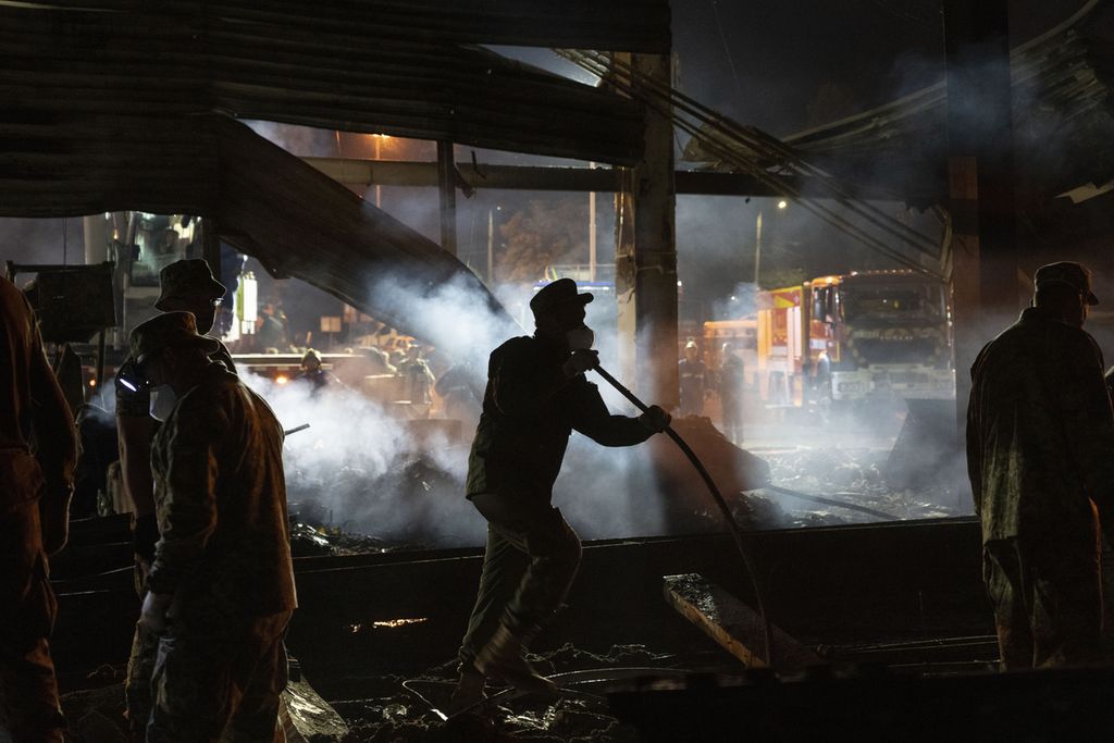 Para sukarelawan dan petugas layanan darurat dari pemadam kebakaran Ukraina tengah berjibaku memadamkan api di sebuah mal di Kremenchuk, Ukraina yang rusak parah akibat dihantam roket Rusia pada Selasa (28/6/2022).