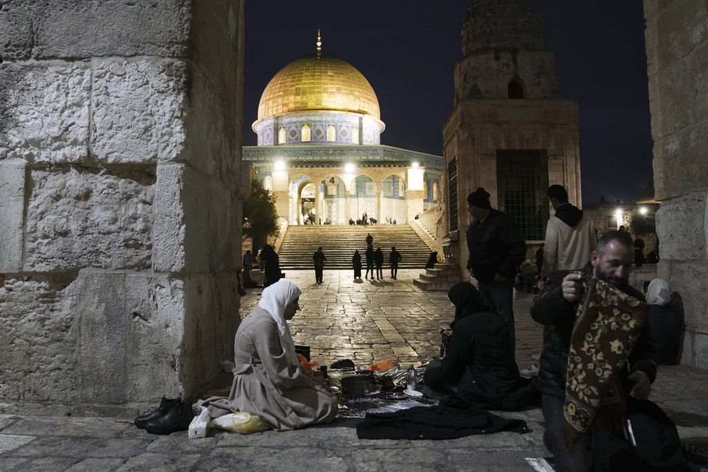 Warga Muslim Palestina berbuka puasa di luar bangunan Kubah Batu (Dome of Rock) di kompleks Masjid Al-Aqsa di Kota Tua Jerusalem Timur pada 16 Maret 2024. 