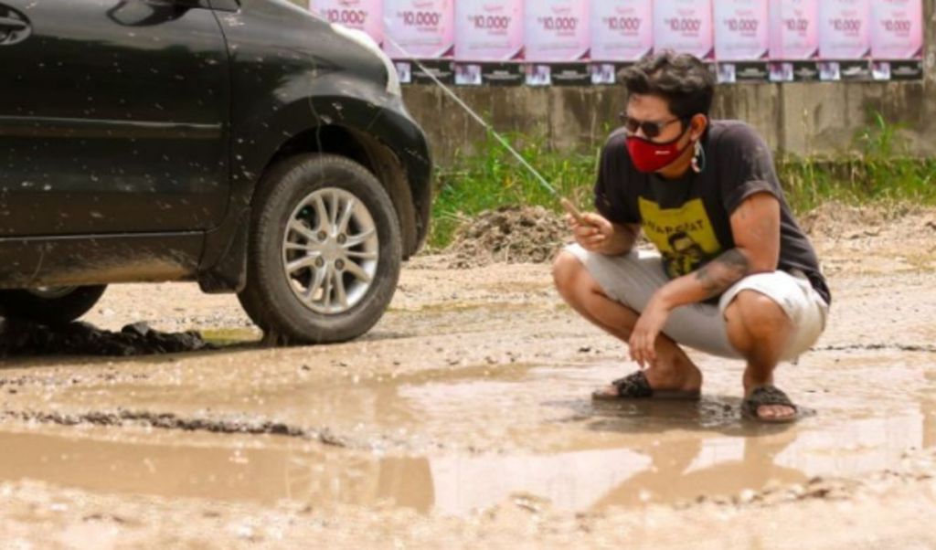 Seorang warga Lampung memilih cara kreatif untuk menggambarkan kondisi jalan rusak di sekitar tempat tinggalnya.