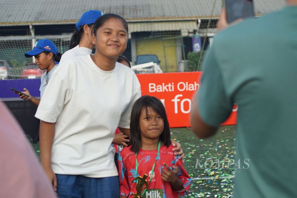 Siswi SDN 004 Cisaranten Kulon, Viona Humaira Nurwidhania (9), berfoto bersama pemain timnas sepak bola putri, Gadhiza Asnanza, setelah gelaran turnamen sepak bola putri antarsekolah dasar dan madrasah ibtidaiyah, MilkLife Soccer Challenge, di lapangan Progresif Sport Center, Bandung, Jawa Barat, Minggu (23/6/2024).