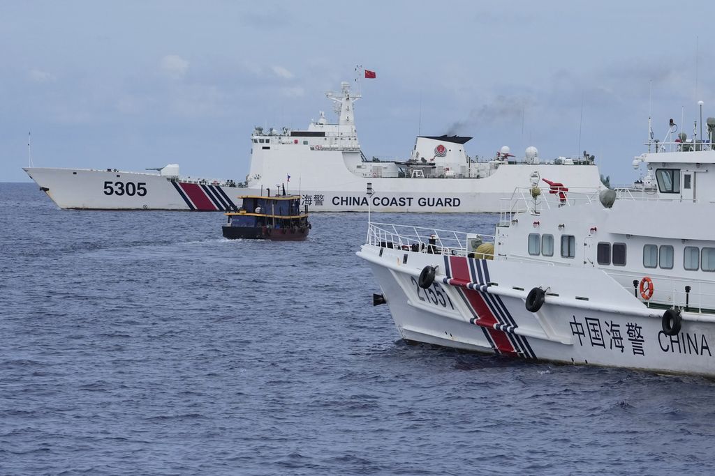 Sebuah perahu pemasok logistik Filipina (tengah) bermanuver di antara dua kapal penjaga pantai China, yang berusaha menghadang, di dekat Beting Second Thomas, atau disebut juga Beting Ayungin dalam bahasa Filipina, di perairan sengketa Laut China Selatan. 