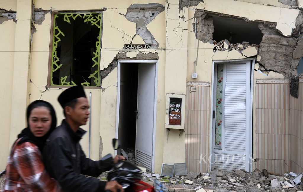 Warga melintas di depan bangunan masjid yang rusak di Desa Kuta Wetan, Kecamatan Cugenang, Kabupaten Cianjur, Kamis (1/12/2022). 