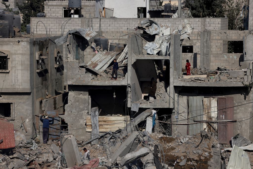 Warga Palestina memeriksa bangunan yang rusak parah akibat pengeboman Israel di Rafah, Senin (4/12/2023).