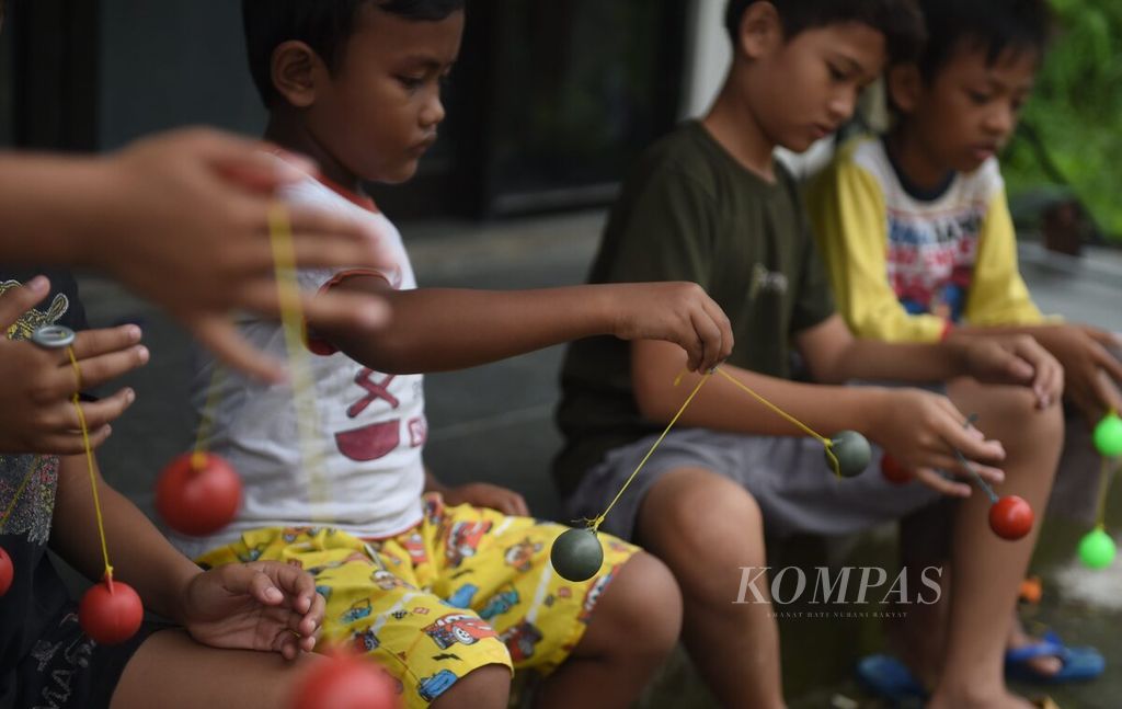 Anak beradu terampil memainkan lato-lato di salah satu kompleks perumahan, Kecamatan Sukodono, Kabupaten Sidoarjo, Jawa Timur, Senin (26/12/2022). 