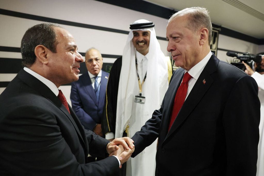 Presiden Turki Recep Tayyip Erdogan (kanan) berjabat tangan dengan Presiden Mesir Abdel Fattah el-Sisi (kiri) disaksikan Emir Qatar Emir Sheikh Tamim bin Hamad al-Thani (kedua dari kanan) saat keduanya bertemu pada upacara pembukaan Piala Dunia 2022 di Stadion Al-Bayt, Al Khor, utara Doha, Qatar, Minggu (20/11/2022). 