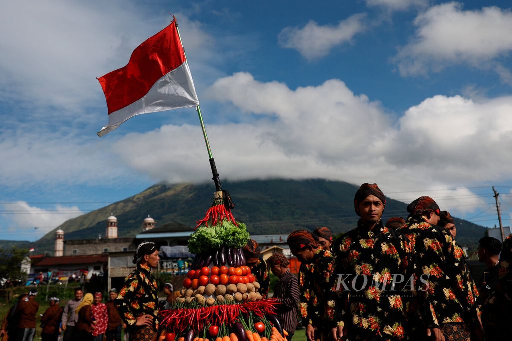 Warga menyiapkan gunungan hasil bumi dengan latar belakang Gunung Sindoro saat menyelenggarakan tradisi nyadran di Desa Kledung, Kecamatan Kledung, Kabupaten Temanggung, Jawa Tengah, Jumat (7/10/2022). 