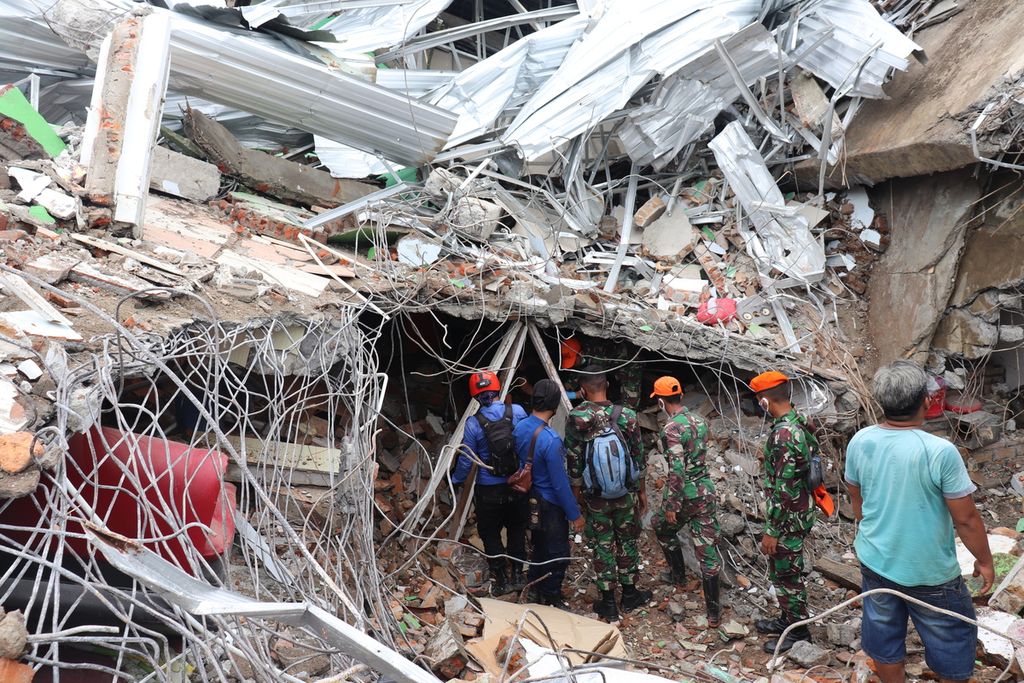 Tim pencarian dan penyelamatan memantau kondisi runtuhan bangunan akibat gempa untuk mengevakuasi dua korban di dalam runtuhan pada Sabtu (16/1/2021) di kawasan komersial di Kelurahan Mamuju, Kecamatan Mamuju, Kabupaten Mamuju, Sulawesi Barat.