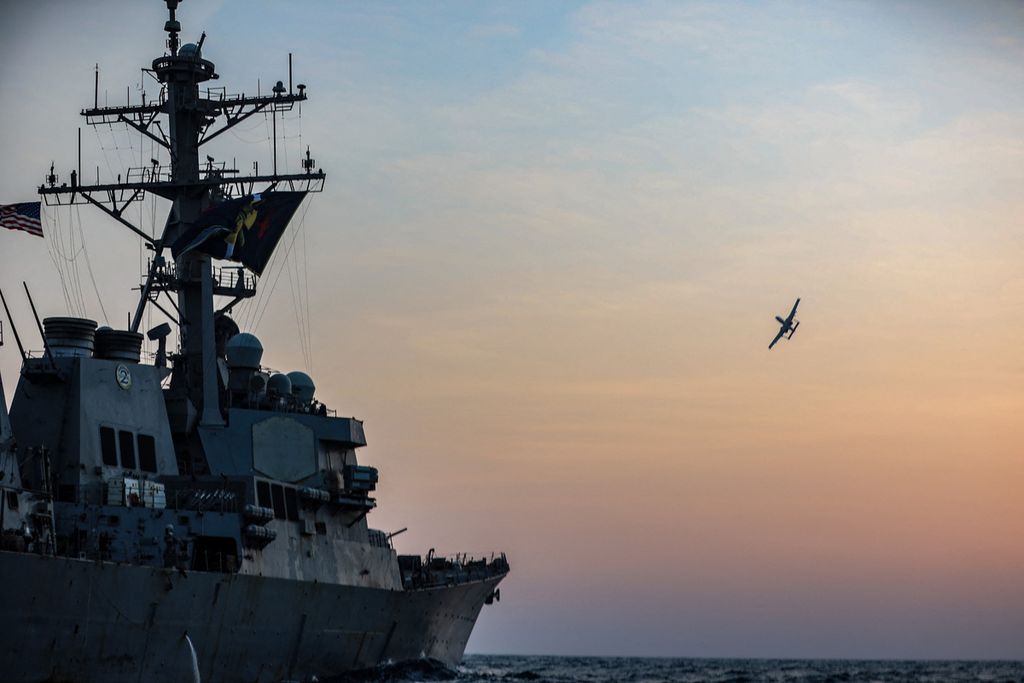 Pesawat militer Amerika Serikat, A-10, melintas dengan latar depan kapal militer USS McFaul dalam sebuah operasi di kawasan Teluk, Timur Tengah, Selasa (15/8/2023). 