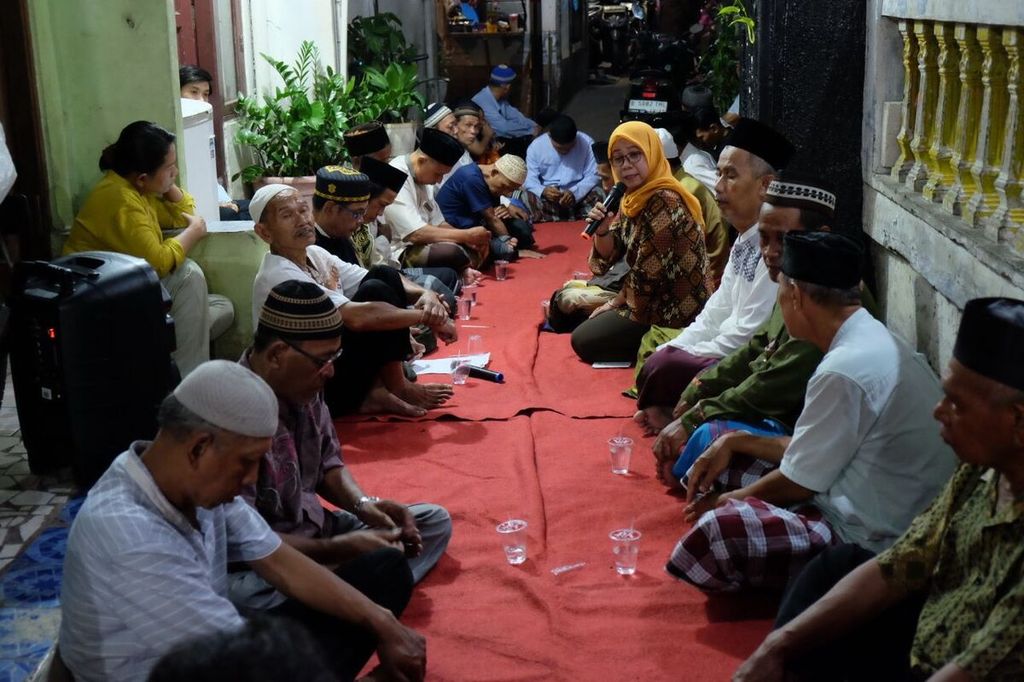 Belasan warga berkumpul di gang kampung selebar sekitar 2 meter di RT 004 RW 008 Jatinegara Kaum, Pulogadung, Jakarta Timur, untuk berdoa bersama untuk para korban Kerusuhan Mei 1998, Jumat (12/5/2023). Malam itu adalah peringatan 25 tahun peristiwa tragis Mei 1998 yang membakar Mal Yogya Klender.