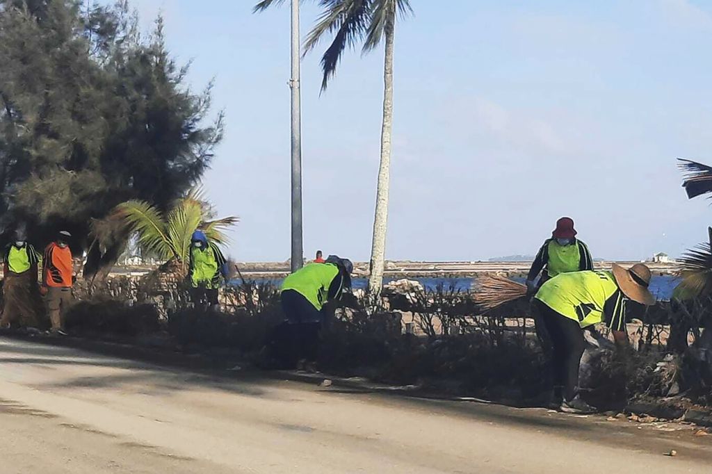 Orang-orang membersihkan puing-puing dari jalan di Nuku'alofa, Tonga, Kamis (20/1/2022). Komunikasi dengan Tonga masih terbatas setelah letusan hari Sabtu dan tsunami merusak kabel serat optik tunggal yang menghubungkan Tonga dengan seluruh dunia.