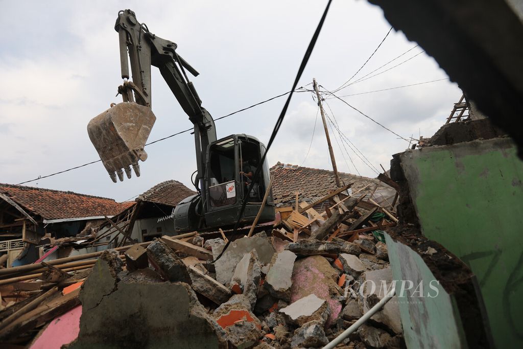 Ekskavator dikerahkan untuk membersihkan puing bangunan rumah warga di lokasi gempa di Kampung Wargaluyu, Desa Nagrak, Kecamatan Cianjur, Kabupaten Cianjur, Jawa Barat, Minggu (4/12/2022).