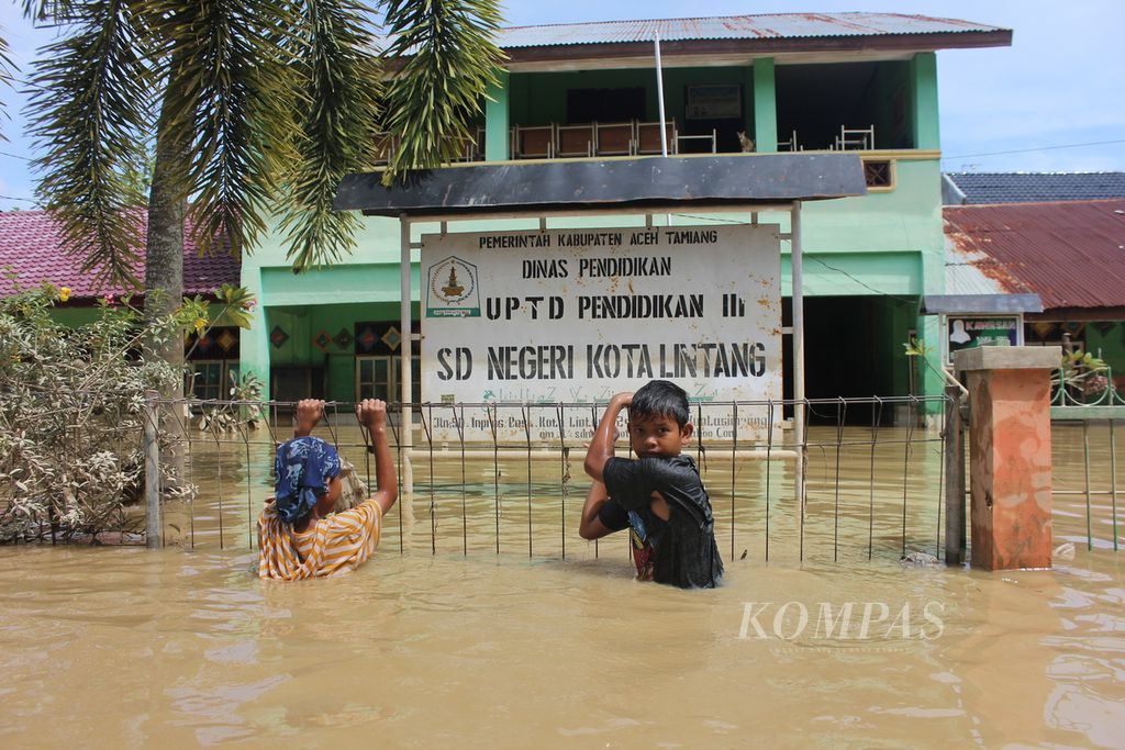 Anak-anak bermain dekat bangunan sekolah yang tergenang banjir di Desa Kota Lintang, Kecamatan Kuala Simpang, Kabupaten Aceh Tamiang, Aceh, Minggu (6/11/2022). Banjir yang terjadi sejak Selasa (1/11/2022) menggenangi 146 desa dan mengakibatkan 29.000 warga mengungsi.