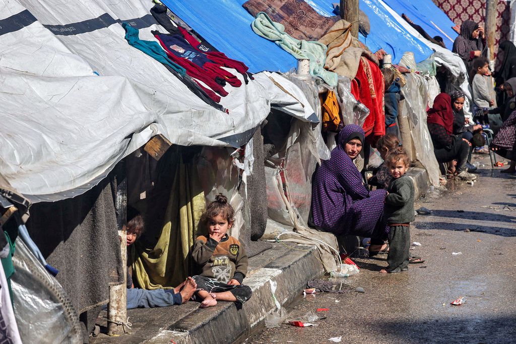 Pengungsi perempuan dan anak duduk di luar tenda di Rafah, kota di Gaza selatan, pada 8 Februari 2024.
