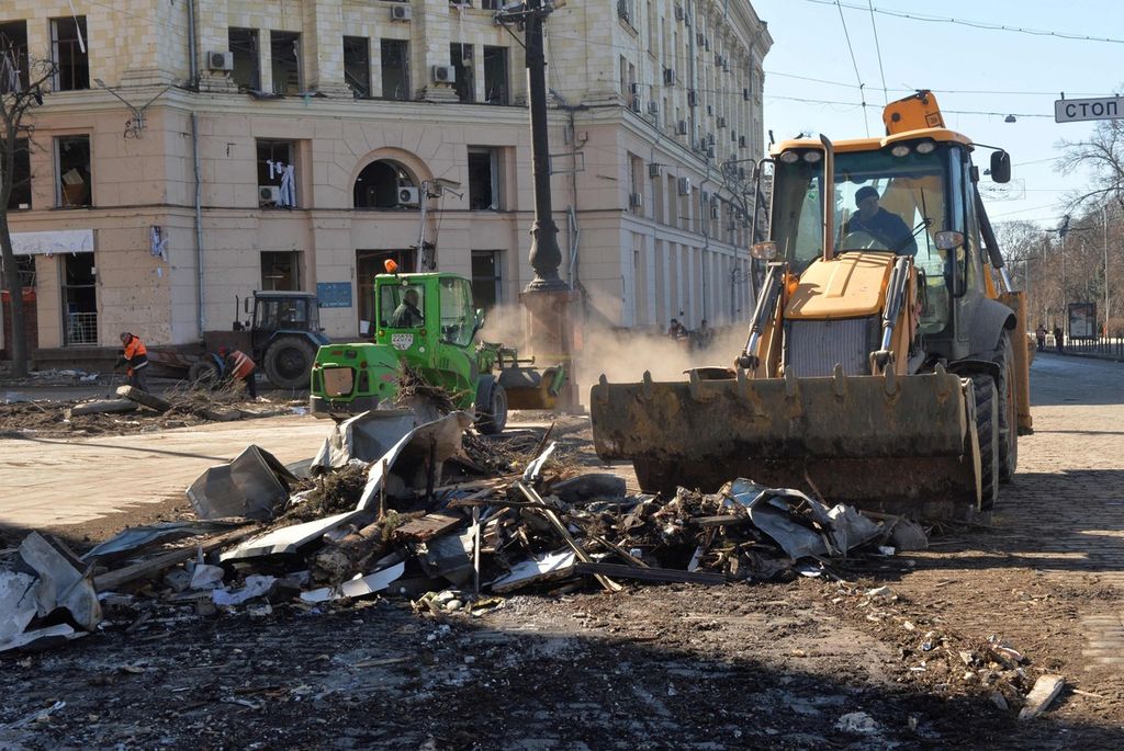 Foto pertama memperlihatkan warga tengah membersihkan salah satu sudut Lapangan Kebebasan atau Freedom Square di Kharkiv, Selasa (22/3/2022). Foto kedua memperlihatkan warga mengisi karung dengan pasir untuk melindungi patung=patung bersejarah di kota itu agar terhindar dari kerusakan akibat serangan Rusia. Foto diambil pada Sabtu (26/3/2022).