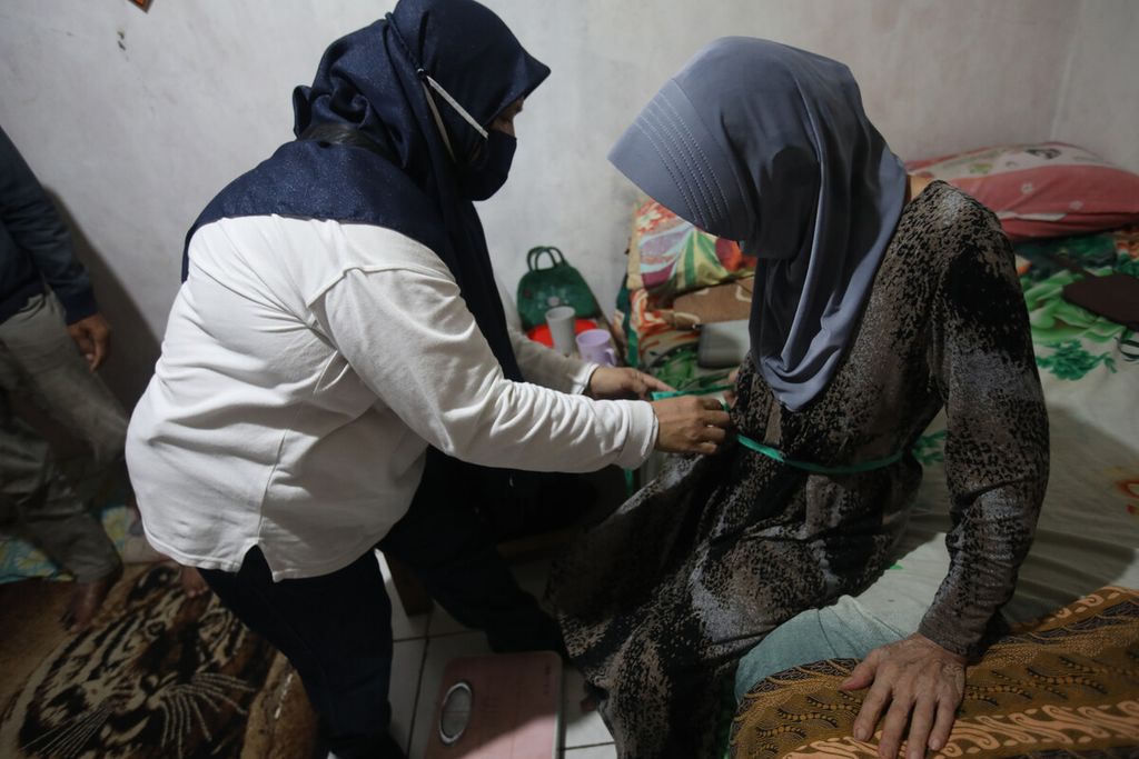 Kader posyandu mengukur lingkar warga perut lansia di tempat tinggalnya di Kampung Gandaria, Pondok Kelapa, Jakarta Timur, Kamis (13/1). Pelayanan jemput bola dari rumah ke rumah ini telah dilakukan kader posyandu selama pandemi. 