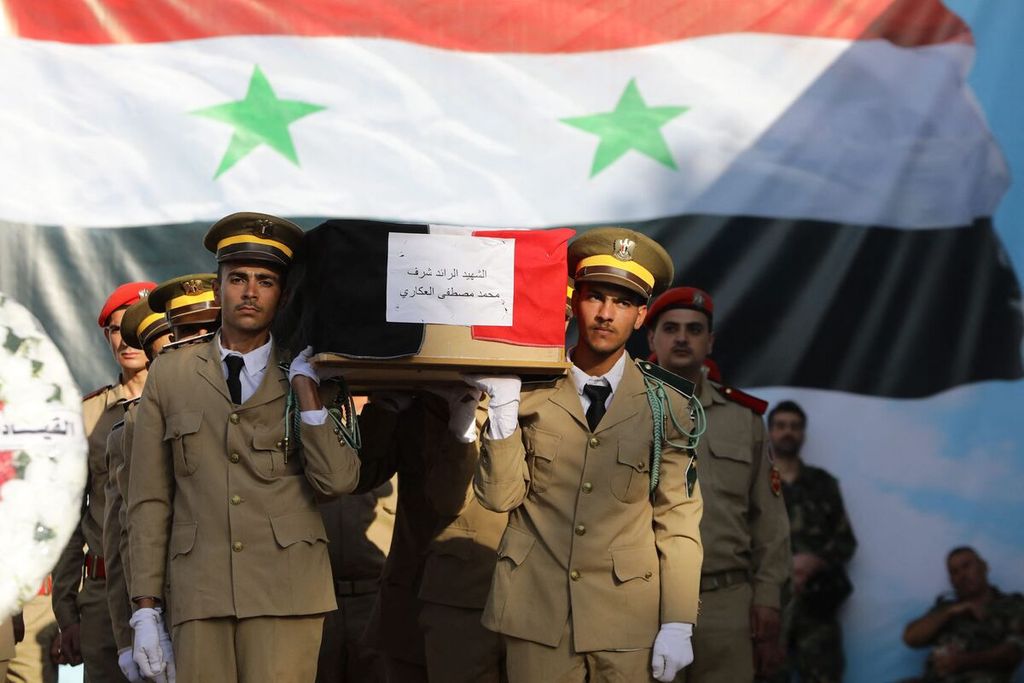 Tentara Suriah membawa peti jenazah korban di luar rumah sakit di Homs, Suriah, Jumat (6/10/2023), dalam pemakaman korban serangan pesawat nirawak di sebuah akademi militer, sehari sebelumnya. 