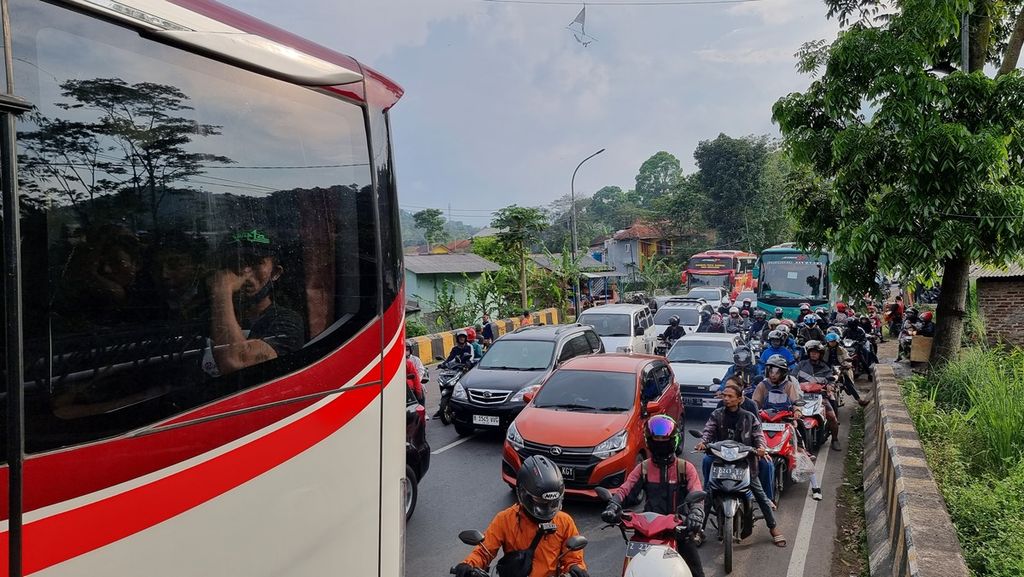 Penumpang bus menunggu bus yang tersendat akibat kemacetan di Jalur Nagreg, Kabupaten Bandung, Jawa Barat, Kamis (20/4/2023). Di jalur ini, arus kendaraan diperdiksi mulai melandai di H-2 Lebaran. Namun, kepadatan masih terjadi di jam-jam tertentu.