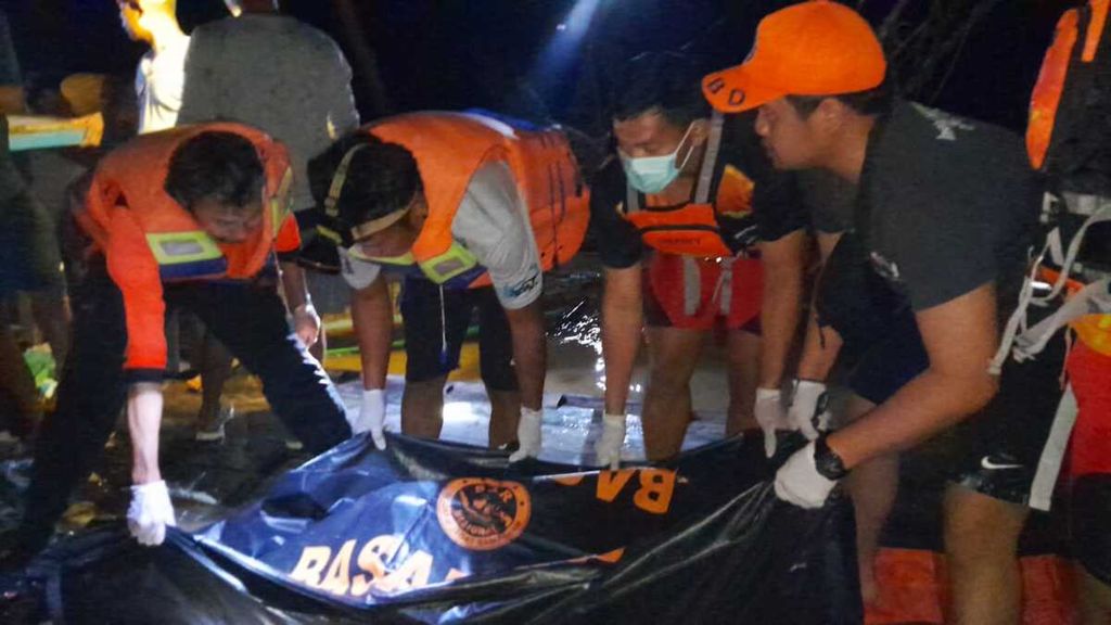 Petugas memasukkan jenazah korban tenggelam akibat perahu terbalik di Sungai Kahayan ke dalam kantong jenazah pada Minggu (9/7/2023).