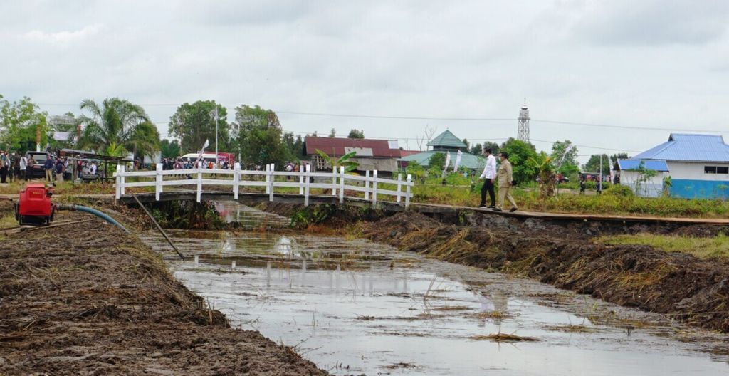 Presiden Joko Widodo dan Menteri Pertahanan Prabowo Subianto berjalan melintasi kanal di lahan yang diproyeksikan menjadi lokasi lumbung pangan (<i>food estate</i>) di Dadahup, Kabupaten Kapuas, Kalteng, 9 Juli 2020.