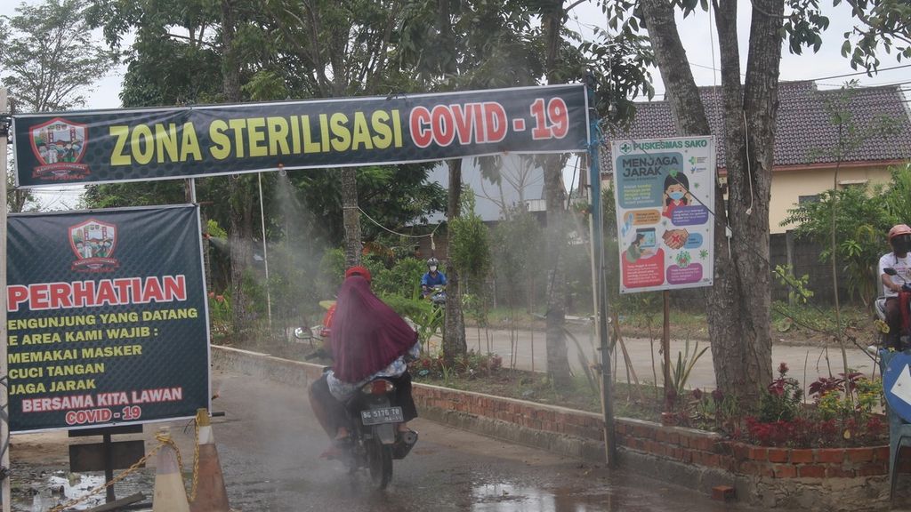 Pengendara motor melintasi alat penyemprot otomatis cairan disinfektan di salah satu Kampung Tangkal Covid-19, di Kompleks Bumi Sako Damai, Kecamatan Sako, Palembang, Jumat (3/7/2020). Keberadaan Kampung Tangkal Covid-19 diharapkan dapat mencegah penularan di Kota Palembang yang hingga saat ini masih berstatus zona merah.