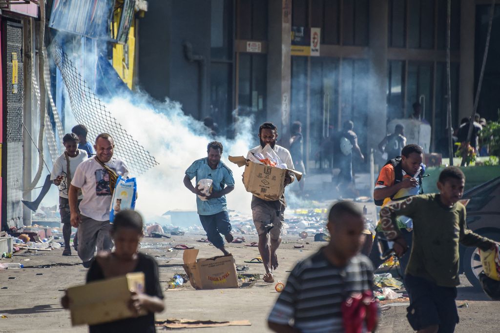 Orang-orang berlarian membawa barang jarahan di tengah kerusuhan di Port Moresby, Papua Niugini, Rabu (10/1/2024). 