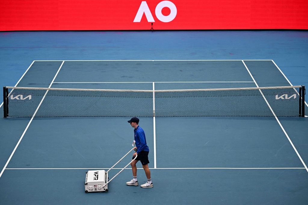 Petugas mengeringkan lapangan setelah hujan reda pada hari ketiga turnamen tenis Grand Slam Australia Terbuka di Melbourne Park, Rabu (18/1/2023). 