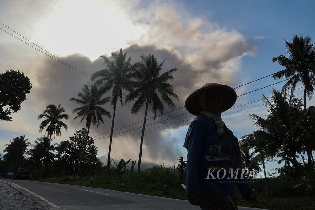 Petani melintas erupsi Gunung Merapi di Desa Krogowanan, Sawangan, Magelang, Jawa Tengah, Minggu (12/3/2023). 