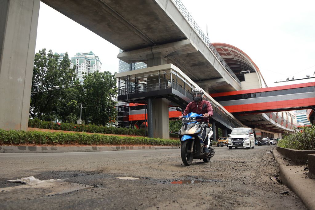 Seorang pengendara motor melintasi Jalan HR Rasuna Said, Jakarta Selatan, yang berlubang, Senin (24/10/2022).