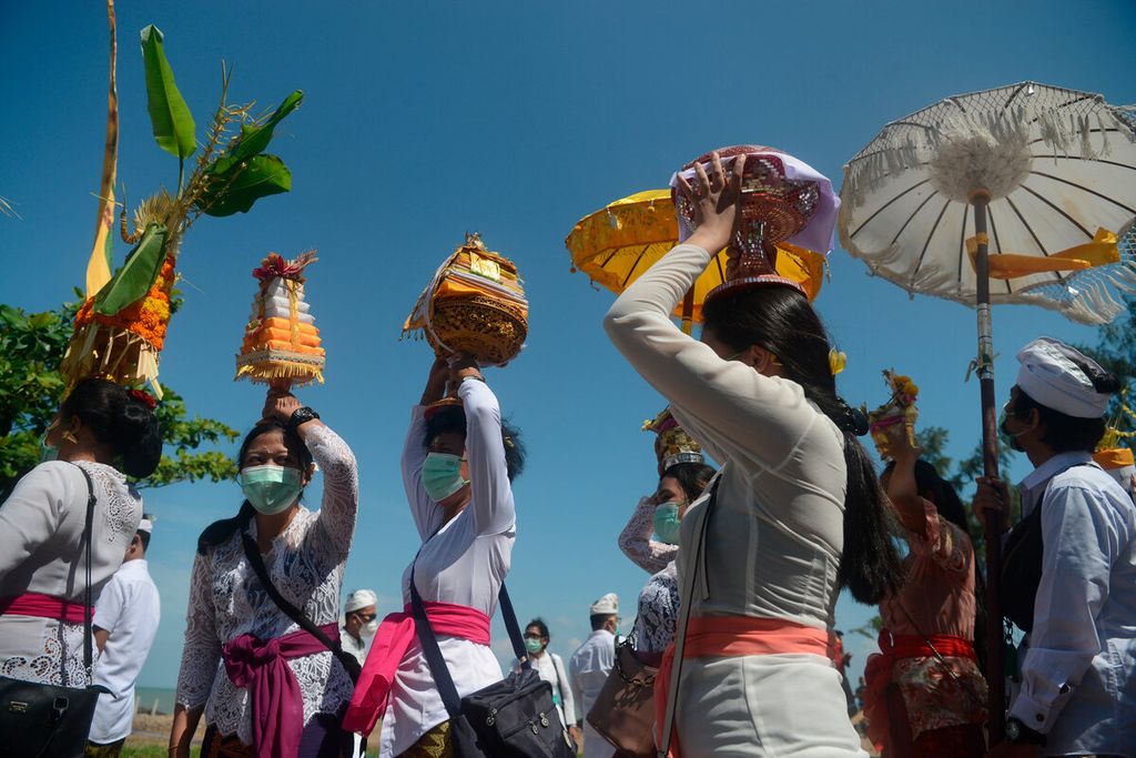 Several women carry prayer equipment and offerings after holding a prayer during the Melasti ceremony at the Beach, Marina, Semarang City, Central Java, Sunday (27/2/2022).