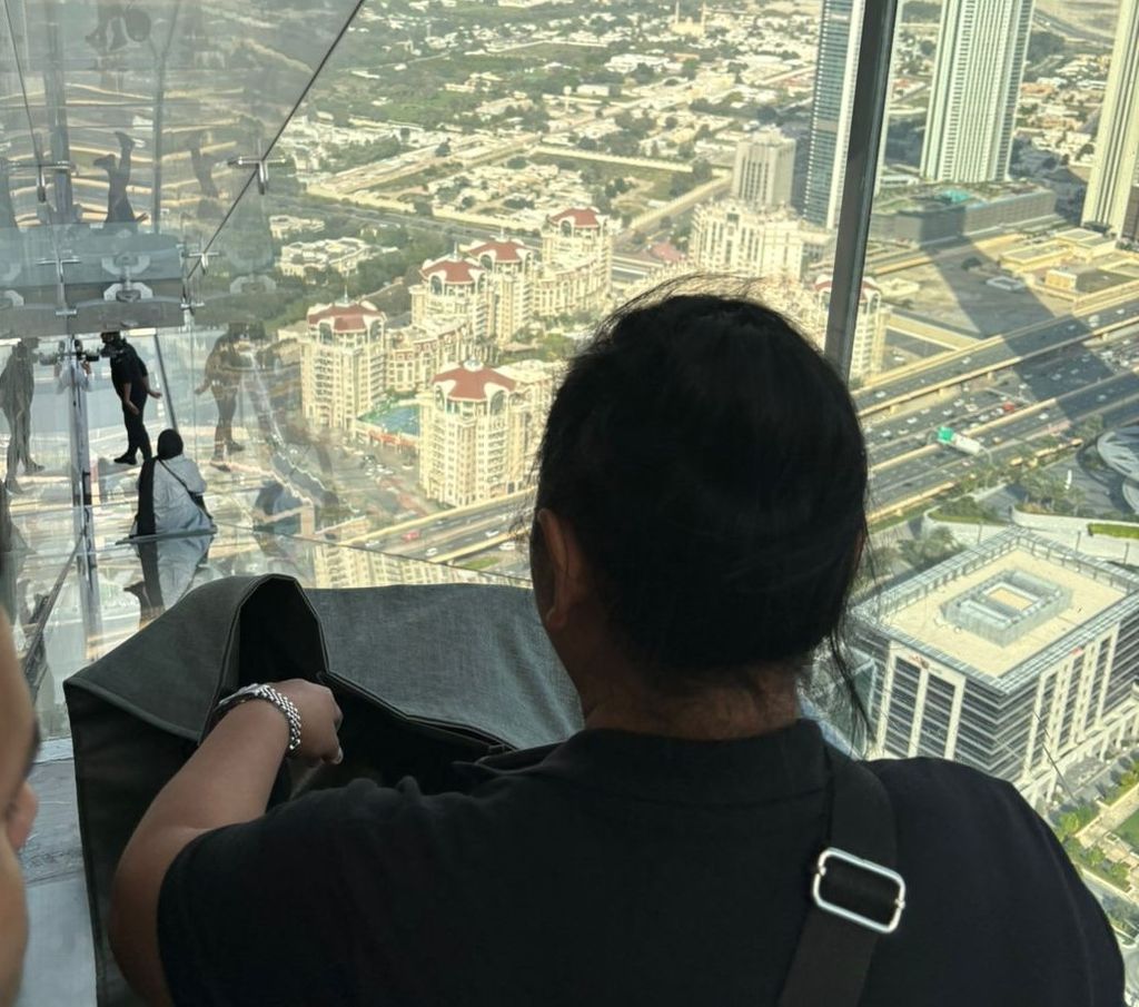 Seorang turis meluncur di balkon kaca dari lantai 53 ke lantai 52 gedung Sky View di kota Dubai, Uni Emirat Arab, Sabtu (23/3/2024). Wisata ini tidak semendebarkan wisata Edge Walk di gedung yang sama.