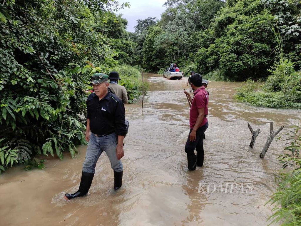 Beberapa anggota staf PT Restorasi Ekosistem Indonesia mengawasi mobil yang menerjang banjir di Hutan Harapan, Jambi, Jumat (9/2/2024).
