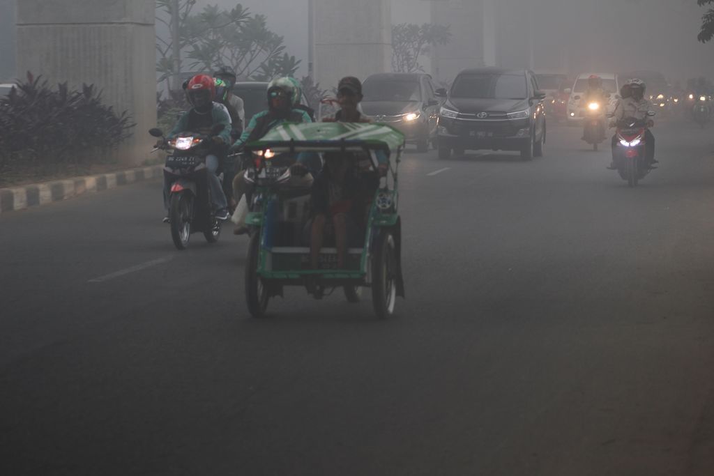 Kondisi kabut asap pekat di Kota Palembang, Sumatera Selatan, Senin (14/10/2019). Pengendara harus menyalakan lampu untuk menghindari kecelakaan. Asap terjadi karena kebakaran lahan di sejumlah daerah, seperti di pinggiran Kota Palembang dan di Kabupaten Ogan Komering Ilir.