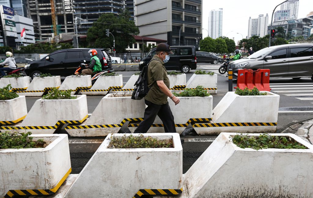 Warga berjalan di jalur pedestrian di Jalan Jenderal Sudirman, Jakarta, Selasa (1/3/2022). Pemerintah berencana mengubah status pandemi Covid-19 menjadi endemi.