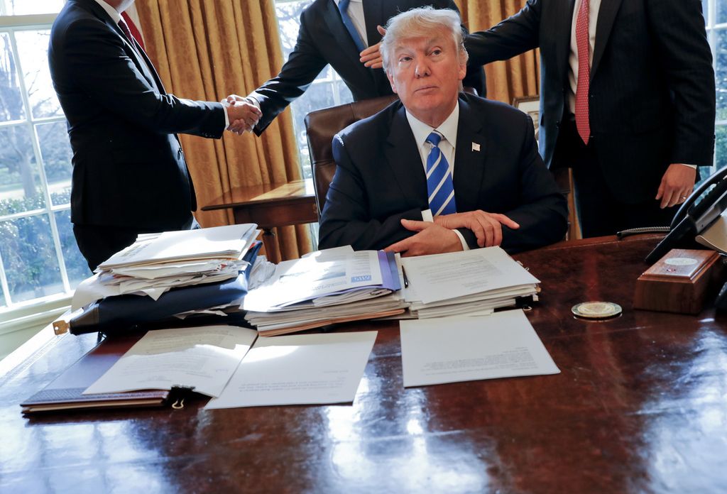 Presiden Amerika Serikat Donald Trump duduk di mejanya setelah pertemuan dengan CEO Intel Brian Krzanich (kiri) dan stafnya di Ruang Oval, Gedung Putih, Washington, 8 Februari 2017. 