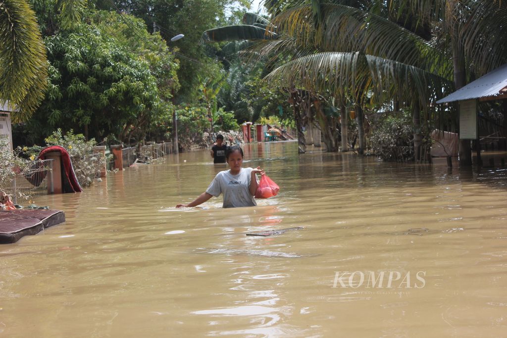 Warga menerobos banjir di Desa Kota Lintang, Kecamatan Kuala Simpang, Kabupaten Aceh Tamiang, Aceh, Minggu (6/11/2022).