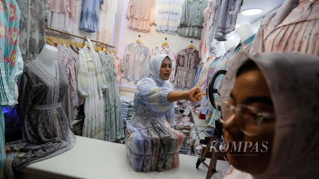 Pedagang menawarkan produk pakaian melalui siaran langsung di media sosial di pusat grosir busana Tanah Abang, Jakarta, Selasa (19/9/2023). 