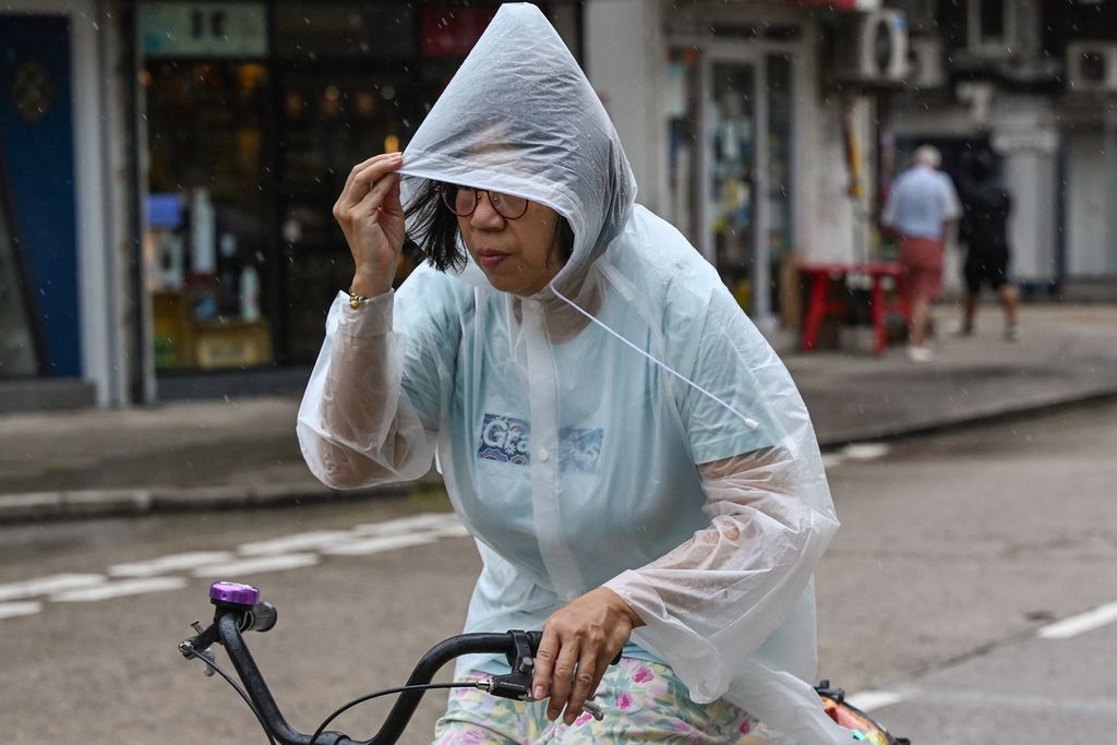 Seorang perempuan mengendarai sepeda di tengah terjangan angin menjelang topan Saola menghantam Hong Kong, September 2023. 