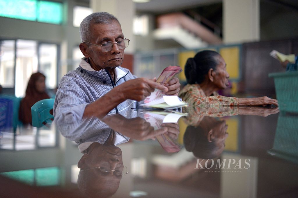Warga menghitung dana pensiun yang diambil di Kantor Pos Besar, Yogyakarta.  