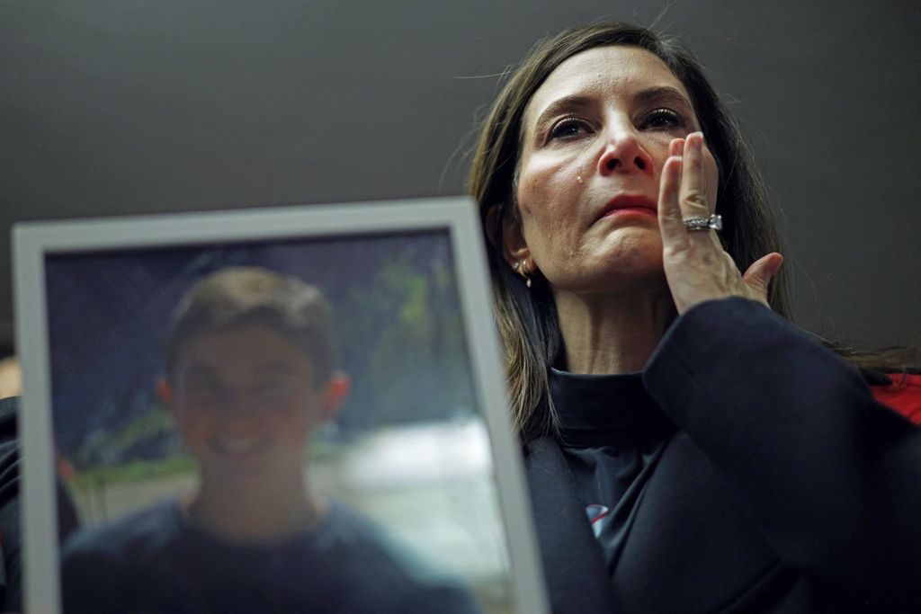 Rose Bronstein dari Chicago, Illinois, menyeka air matanya saat memegang foto putranya, Nate, yang bunuh diri pada 2022 setelah menjadi korban <i>cyberbullying</i>, dalam konferensi pers setelah sidang di Komite Senat, di Capitol Hill, Washington, DC, AS.