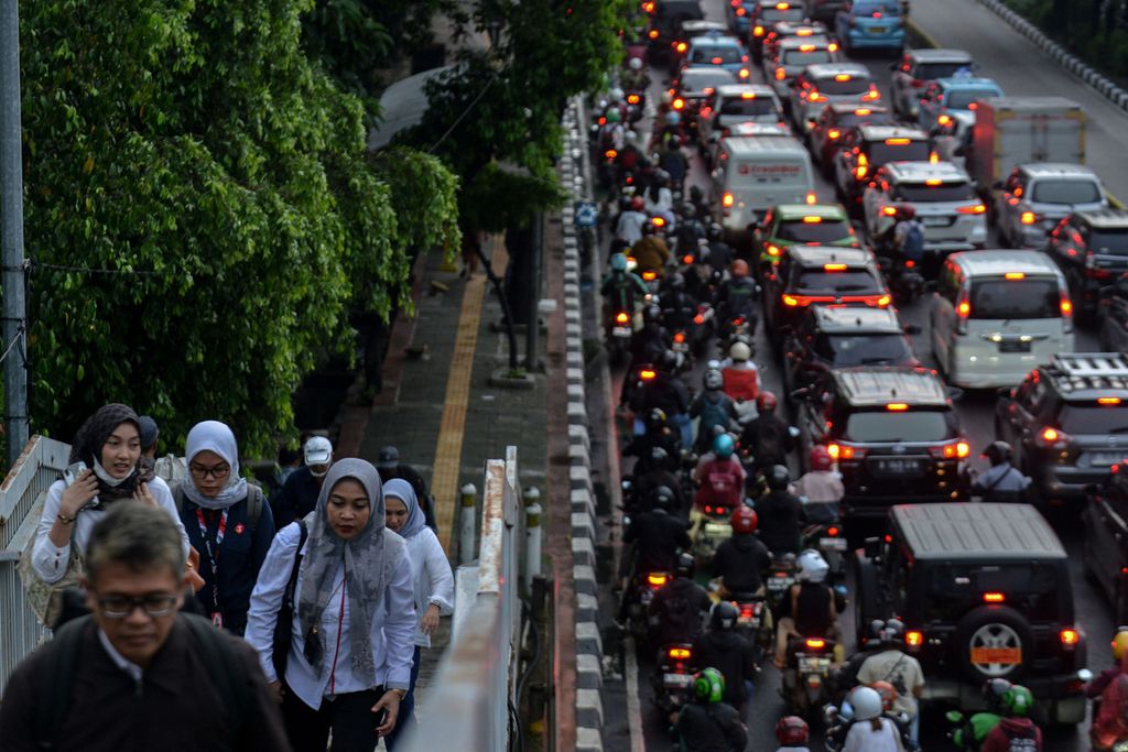 Para pekerja menaiki anak tangga jembatan penyeberangan orang di Jalan Gatot Subroto, Jakarta, saat jam pulang kerja, Senin (19/6/2023).