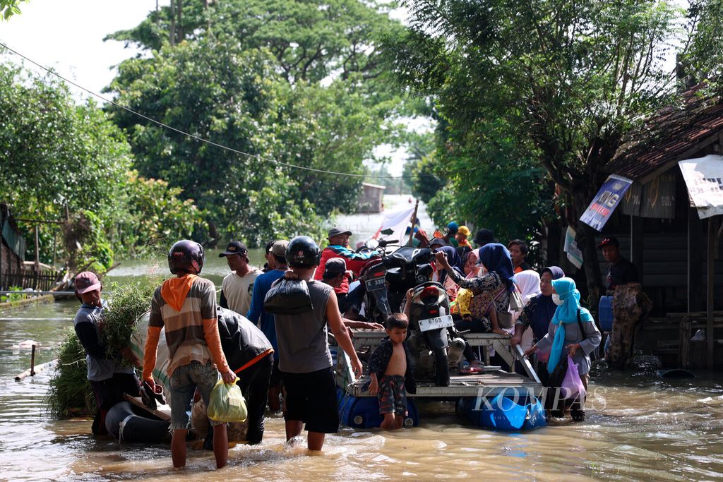 Warga menggunakan perahu melintasi banjir yang menyebabkan permukiman mereka terisolasi, Rabu (4/1/2023), di Desa Kedungdowo, Kecamatan Kaliwungu, Kabupaten Kudus, Jawa Tengah, Rabu (4/1/2023). 