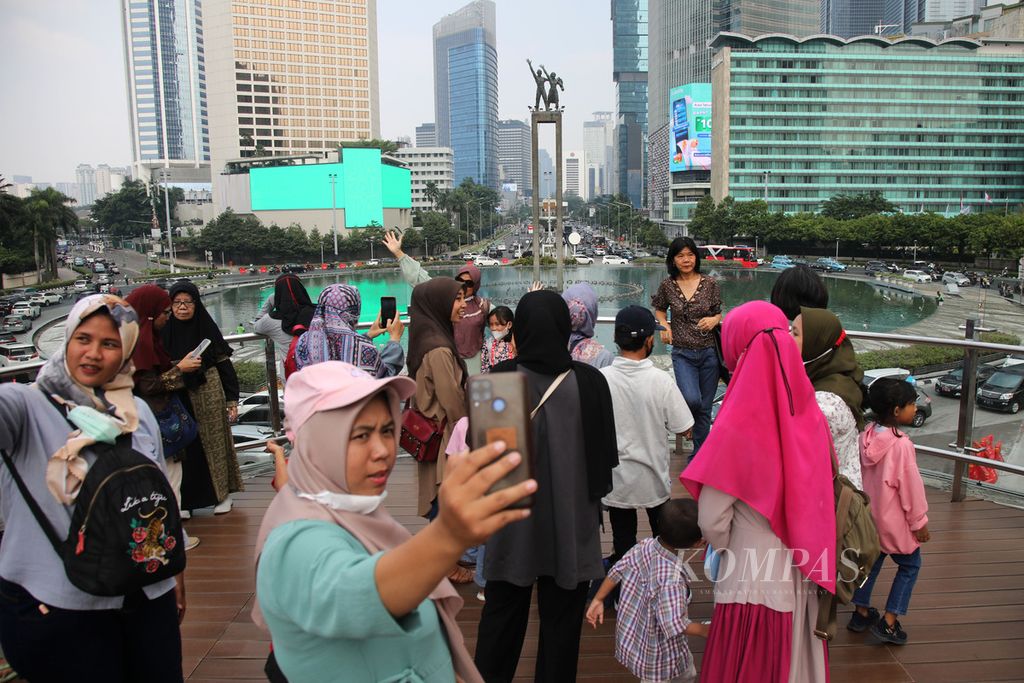 Warga menikmati pemandangan kawasan Bundaran Hotel Indonesia di anjungan Halte Transjakarta Bundaran HI, Jakarta, Kamis (22/6/2023). Kawasan Bundaran HI menjadi salah satu lokasi ikonik atau landmark Kota Jakarta yang berulang tahun ke-496 pada 22 Juni 2023 ini.