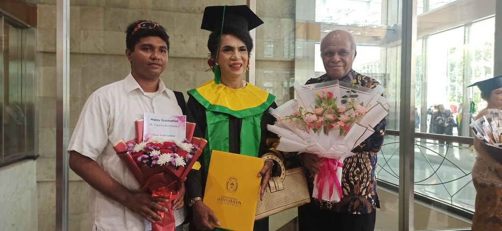 Mami Yuli (62), Ketua Forum Komunikasi Waria Indonesia (tengah), foto bersama pamannya (paling kanan) dan anak angkatnya (paling kiri) saat diwisuda sebagai doktor pada Program Studi Ilmu Hukum, Pascasarjana, Universitas Jayabaya, Jakarta. 