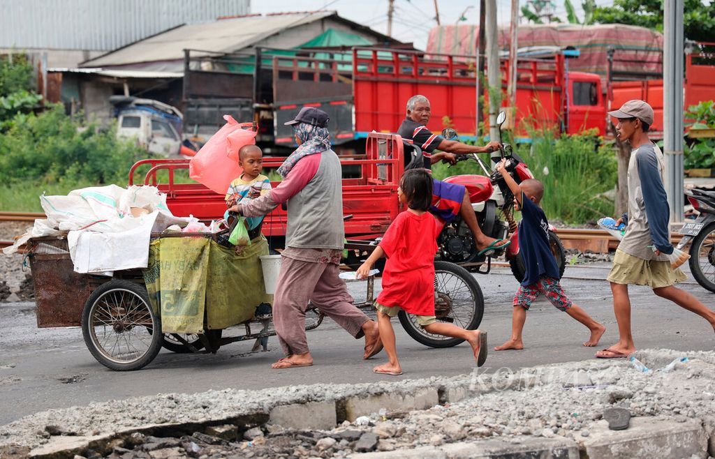 Satu keluarga berjalan beriringan dengan gerobaknya saat mereka memulung sampah yang dapat dijual di Jalan Kaligawe, Kota Semarang, Jawa Tengah, Rabu (22/2/2023). Minimnya akses ekonomi, kesehatan, hingga pendidikan menyebabkan kemiskinan terus mengakar pada kelompok warga miskin ekstrem.