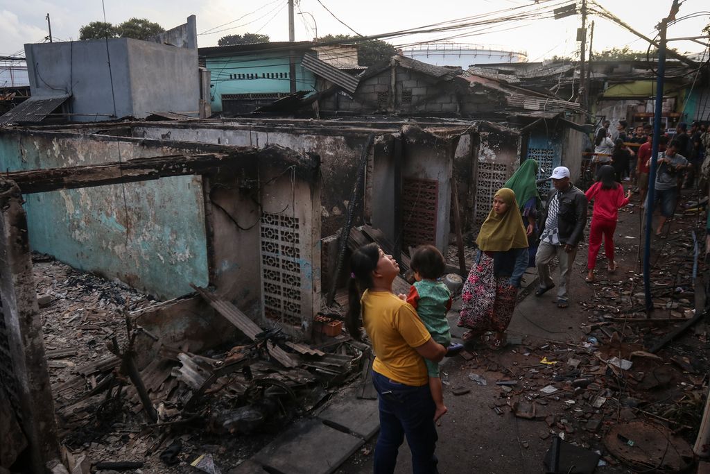 Warga melintas di antara puing rumah yang terbakar di Jalan Tanah Merah Bawah, Rawa Badak Selatan, Koja, Jakarta Utara, Sabtu (4/3/2023). Warga memadati permukiman terdampak kebakaran Depo Pertamina Plumpang untuk memungut barang-barang yang tersisa. 