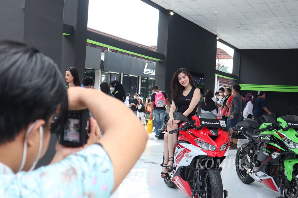Seorang <i>sales promotion girl</i> (SPG) produk sepeda motor asal Jepang tengah difoto pengunjung Jakarta Fair Kemayoran, Jakarta Pusat, Sabtu (18/6/2022). Keberadaan SPG dalam kegiatan pameran industri itu memang kerap hanya berfungsi sebagai pemanis.
