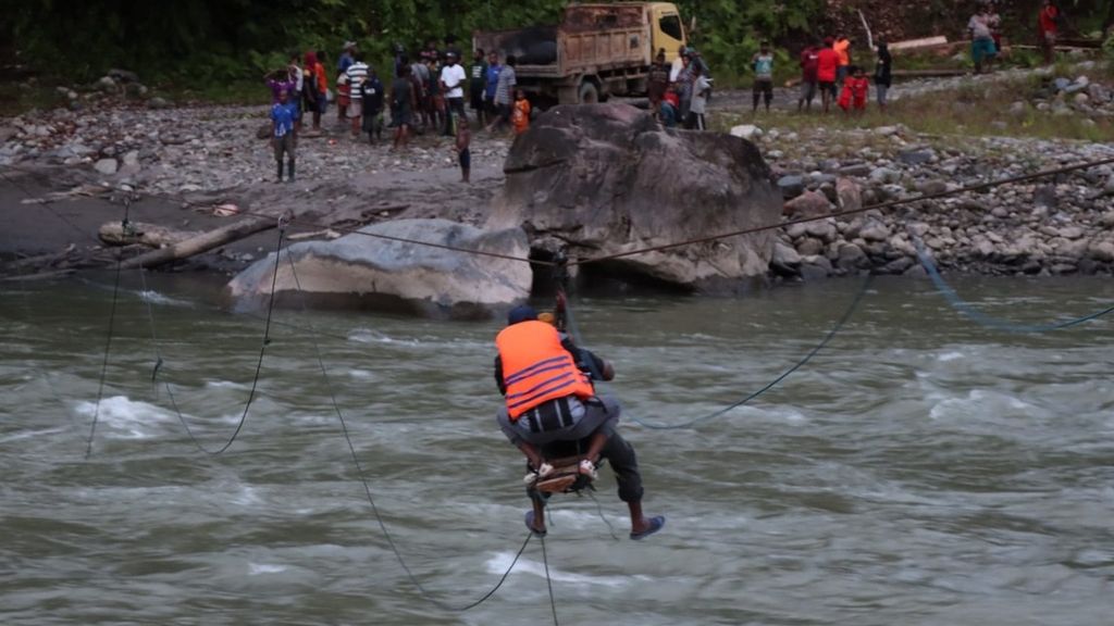 Warga menggunakan tali untuk melintasi Sungai Digul setelah jembatan gantung terputus di Distrik Iwur, Kabupaten Pegunungan Bintang, Papua Pegunungan, Minggu (29/1/2023).
