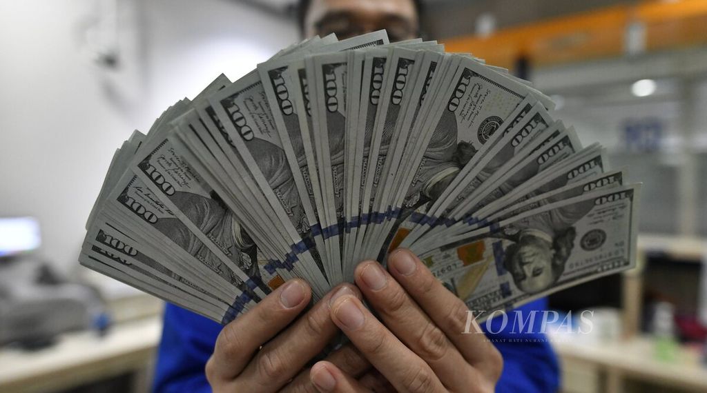 Seorang petugas menunjukkan mata uang dollar AS di sentra kas PT Bank Mandiri (Persero) Tbk, Jakarta, Selasa (5/4/2022).